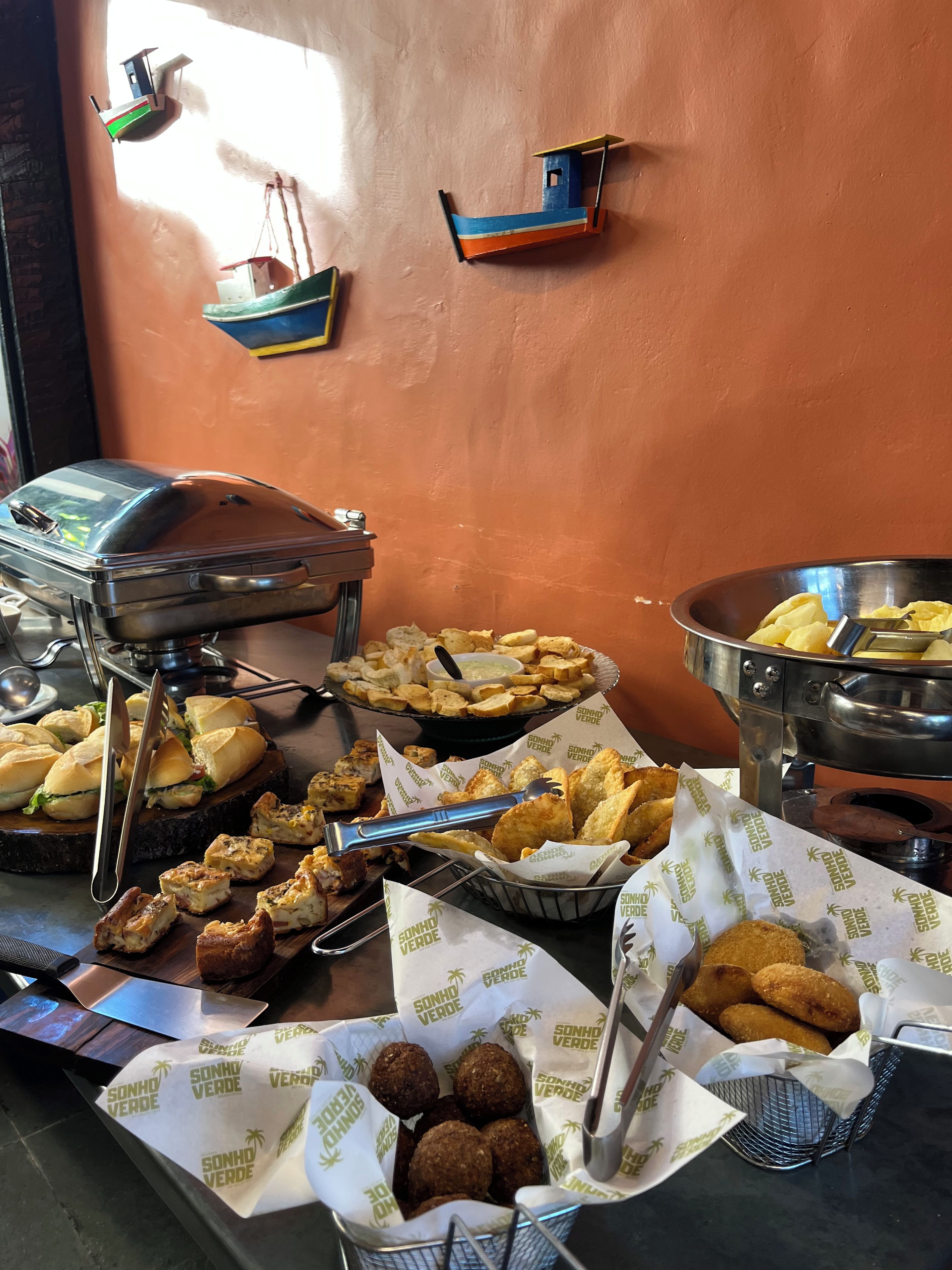 A buffet table with various food items, including sandwiches, fried items, and a bowl of chips.