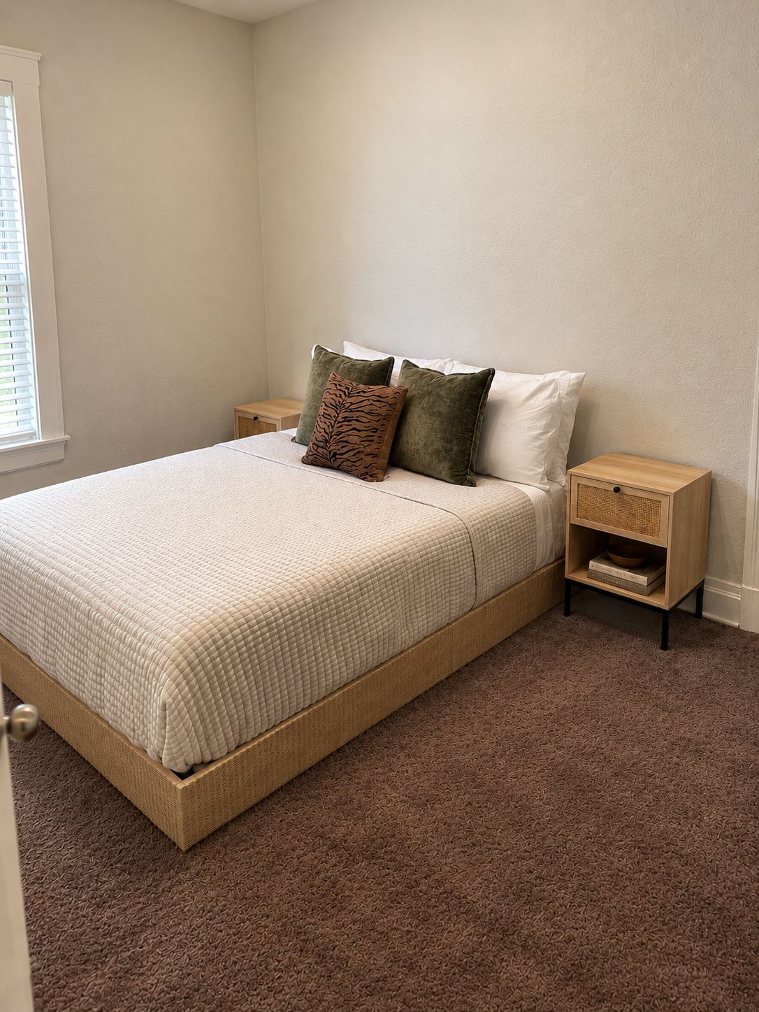 A bedroom with a bed, pillows, a nightstand, and a bedside table.
