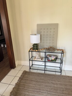 A corner with a black metal shelf holding a lamp, decorative items, and a small basket. - Quaint 2-bedroom house in Detroit perfect for your getaway (Detroit)