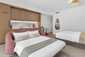 Quarto moderno com cama grande, mesa de cabeceira, espelho e cozinha integrada.