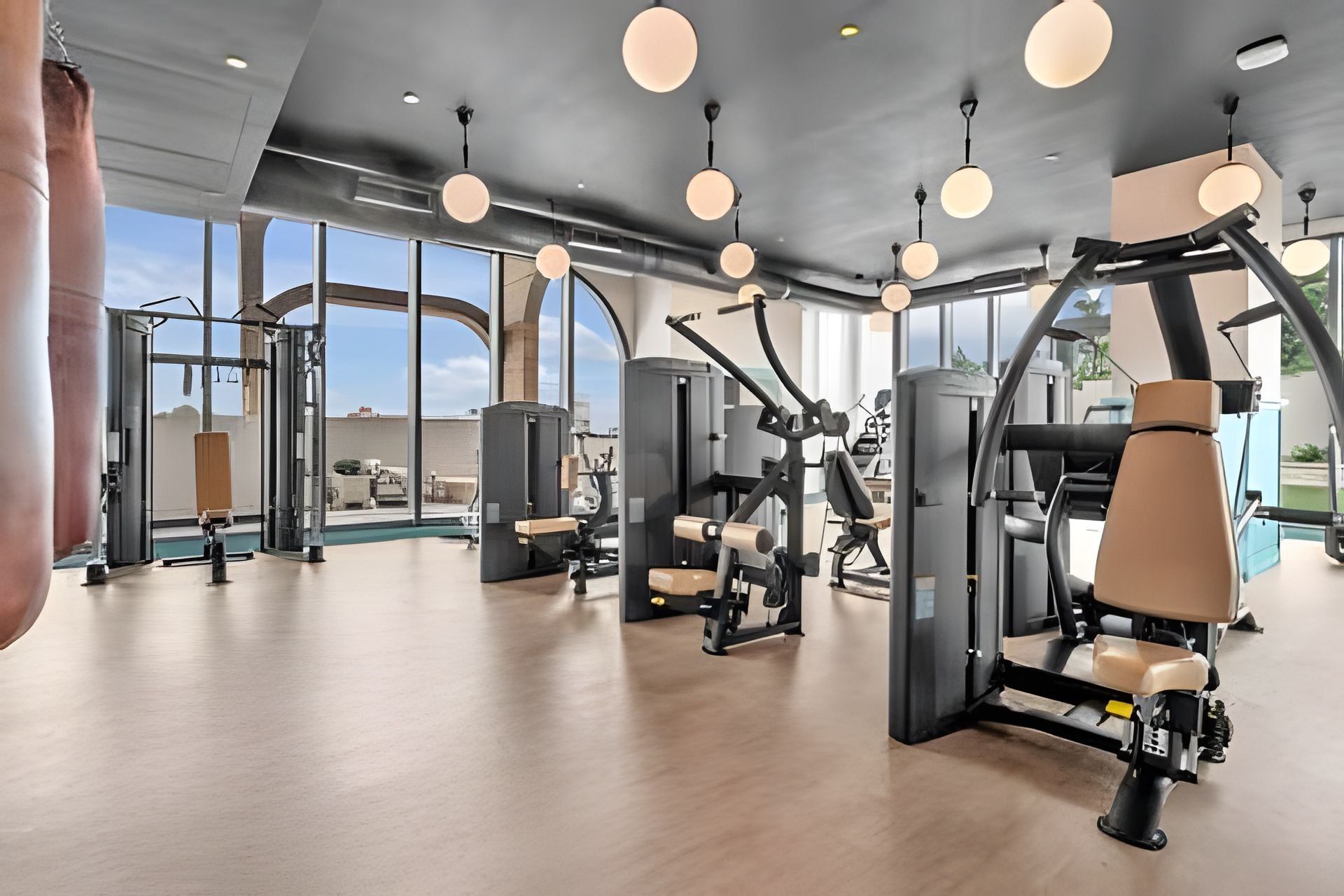 Un gimnasio con diversas máquinas de ejercicio, ventanas amplias y un diseño moderno de techo.