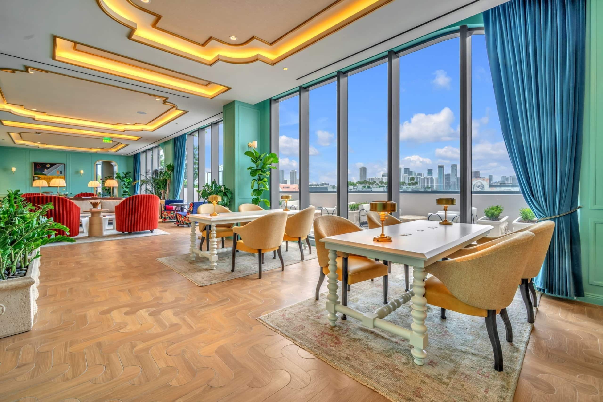 Un espace de restauration moderne offrant une vue sur la ville, de grandes fenêtres et différents types d’aménagements pour s’asseoir.