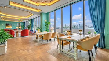 Un espace de restauration moderne offrant une vue sur la ville, de grandes fenêtres et différents types d’aménagements pour s’asseoir.