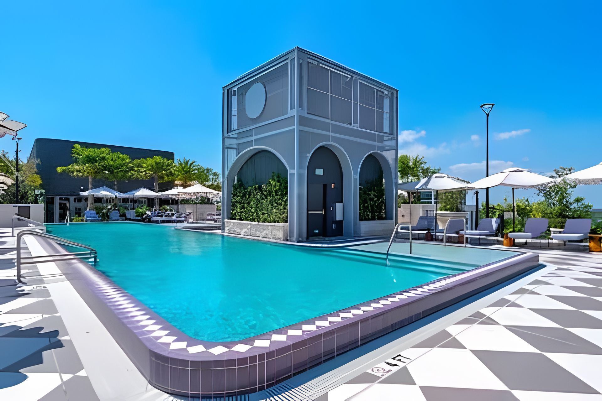 Une piscine dotée d’une structure de bâtiment moderne, de chaises longues et de parasols.