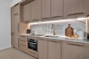 Una cocina moderna con electrodomésticos integrados, encimera de mármol y muebles de madera.