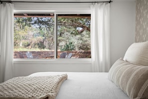 A bedroom with a large bed, a window with curtains, and a view of a garden. - <5min walk to trailhead, quiet escape w/ hot tub (Sedona)