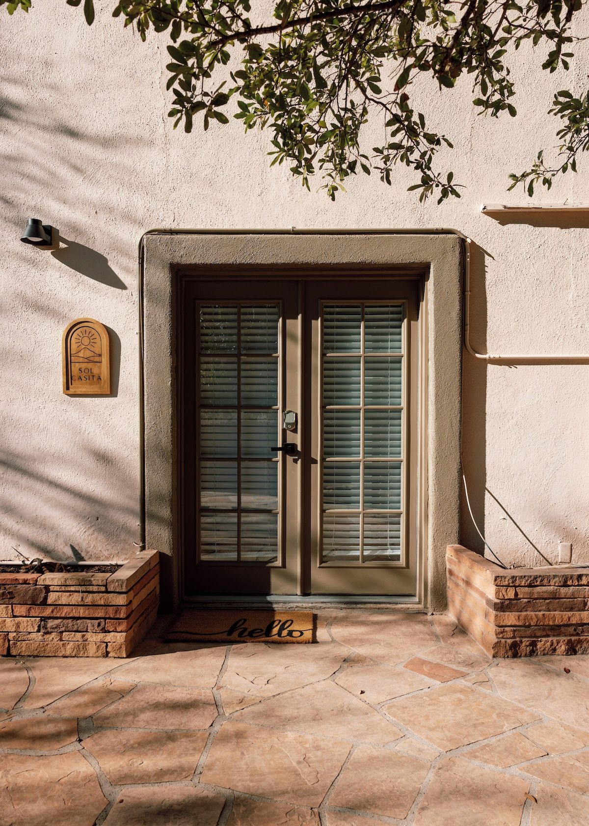 A building entrance with a double door, a welcome mat, and a sign on the wall.