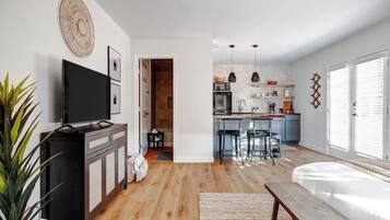 A modern living room with a flat-screen TV, a wooden cabinet, and a large plant.
