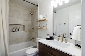 Un bagno moderno con vasca, servizi igienici, mobile lavabo e un grande specchio.