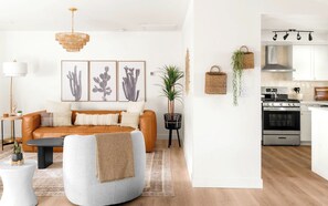 A modern living room with a sofa, coffee table, and a dining area with a kitchen visible. - Modern West Sedona Retreat - hot tub, firepit (Sedona)