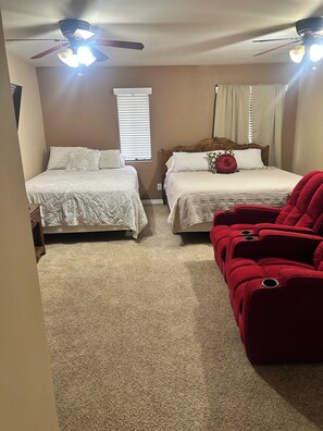 A bedroom with two beds, a ceiling fan, a window with blinds, and a red chair. -  Snowbird Friendly. Monthly Discount
Delightful 4-bedroom home in Bullhead City. (Bullhead City)