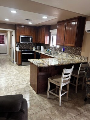 A kitchen with wooden cabinets, a granite countertop, a built-in microwave, and a stainless steel sink. -  Snowbird Friendly. Monthly Discount
Delightful 4-bedroom home in Bullhead City. (Bullhead City)