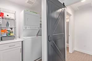 A laundry area with a washing machine, a drying rack, and shelves with cleaning supplies. - Modern 2BR Phoenix Home | Near RoRo + Parking (Phoenix)
