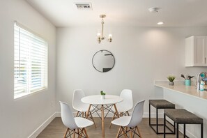 A modern kitchen with white cabinets, a round mirror, and a dining area with a white table and chairs. - Modern 2BR Phoenix Home | Near RoRo + Parking (Phoenix)