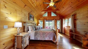 A wooden cabin bedroom with a bed, a nightstand, a dresser, and a ceiling fan. - Thunder Mountain Lodge (Blue Ridge)