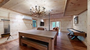 A wooden interior with a pool table, a billiards rack, a sofa, and a unique chandelier. - Thunder Mountain Lodge (Blue Ridge)