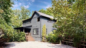 A two-story building with a porch and a gravel driveway.