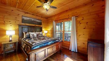 A wooden cabin bedroom with a bed, nightstands, a ceiling fan, and a window with curtains.