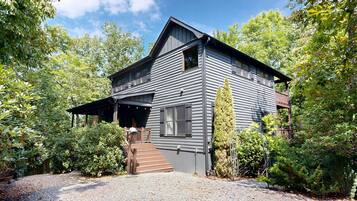 A two-story house with a covered porch and a staircase leading to the entrance.