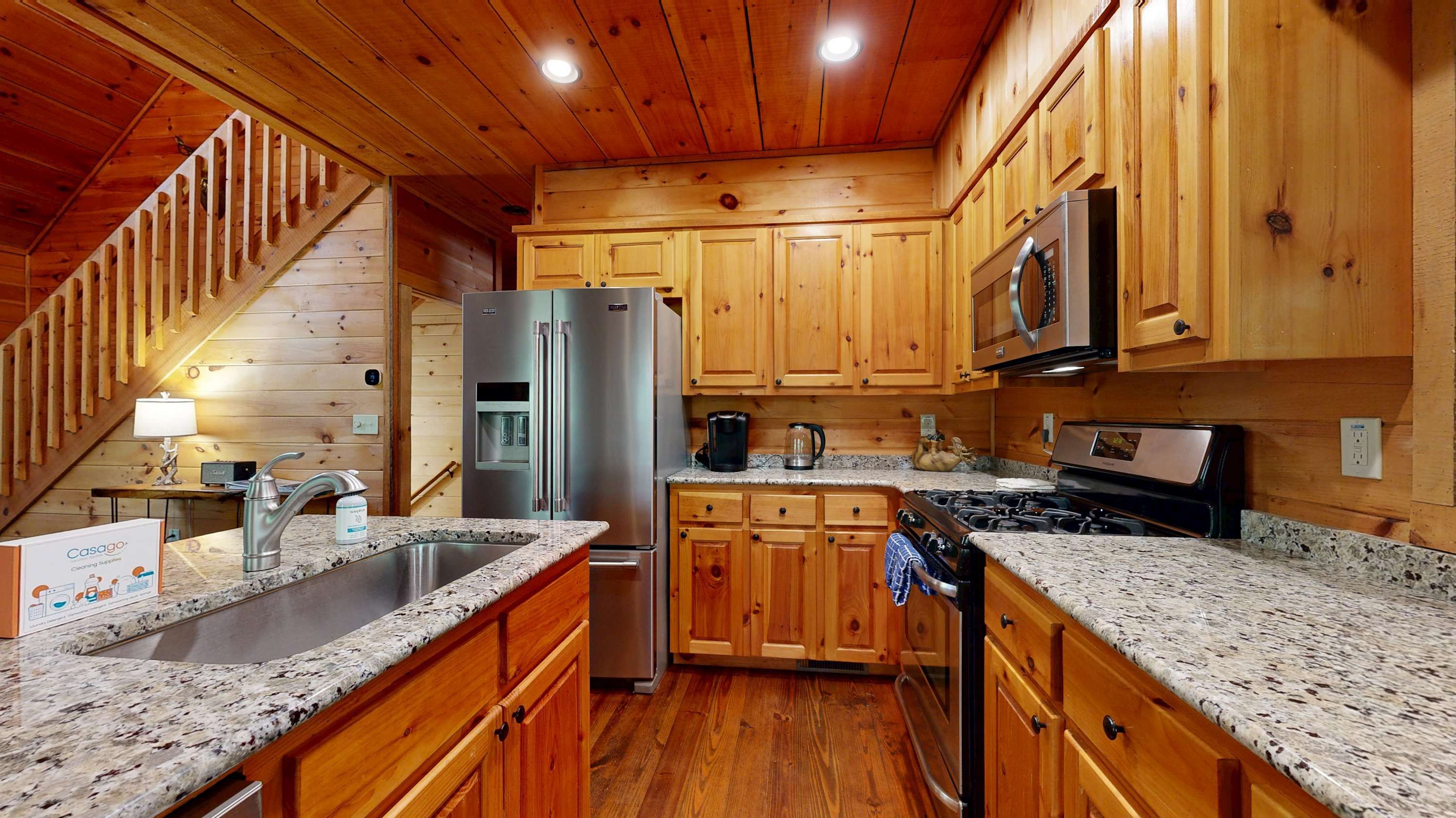 A kitchen with wooden cabinets, granite countertops, stainless steel appliances, and a built-in microwave.