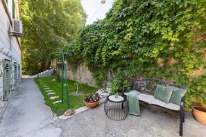 A garden area with a bench, a table, and a potted plant. - Bartulin residence (Split)