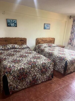A room with two beds, each with a floral-patterned bedspread and wooden headboards.