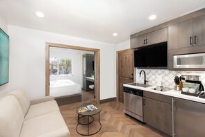 A modern kitchen with stainless steel appliances, wooden cabinets, and a dining area with a sofa and a small round table. - Westgate Park City Resort Unit (Canyons Village), Ski In Ski Out, Valet and more (Park City)