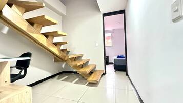 Un interior moderno con una escalera de madera que lleva a un dormitorio.