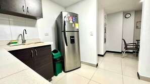 A kitchen with a stainless steel refrigerator, a sink, and a trash bin. - Tolupa Apartamentos (Medellín)