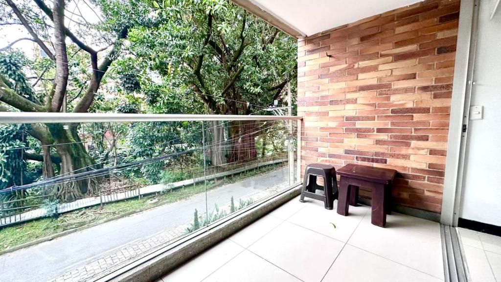 Uma varanda com vista para uma estrada e árvores, um muro de tijolos e um banco.