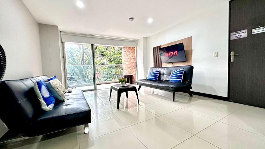 A modern living room with a sofa, a small table, and a television mounted on the wall.