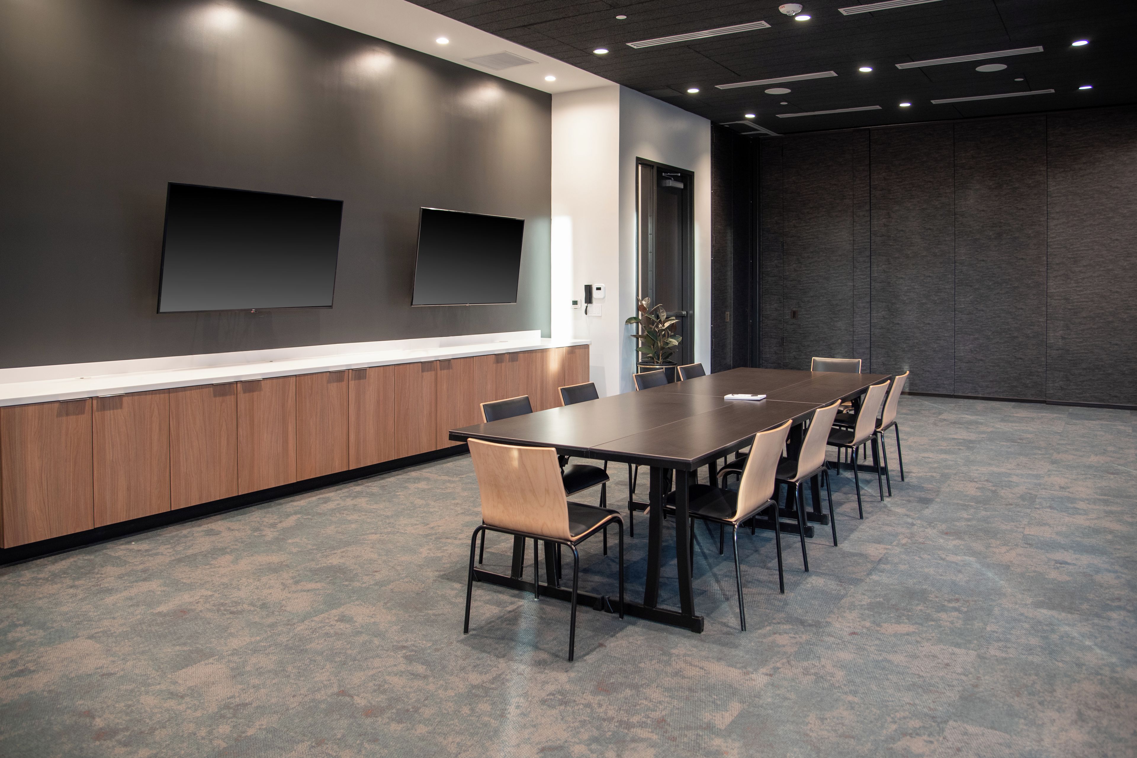 Uma sala de conferências com uma mesa comprida, cadeiras, um quadro branco e uma televisão de tela plana presa à parede.