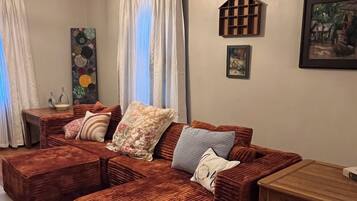 Una sala de estar acogedora con un sofá modular, una mesa de centro de madera y un cuadro en la pared.