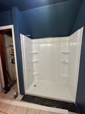 A corner shower with a white interior and a blue wall.