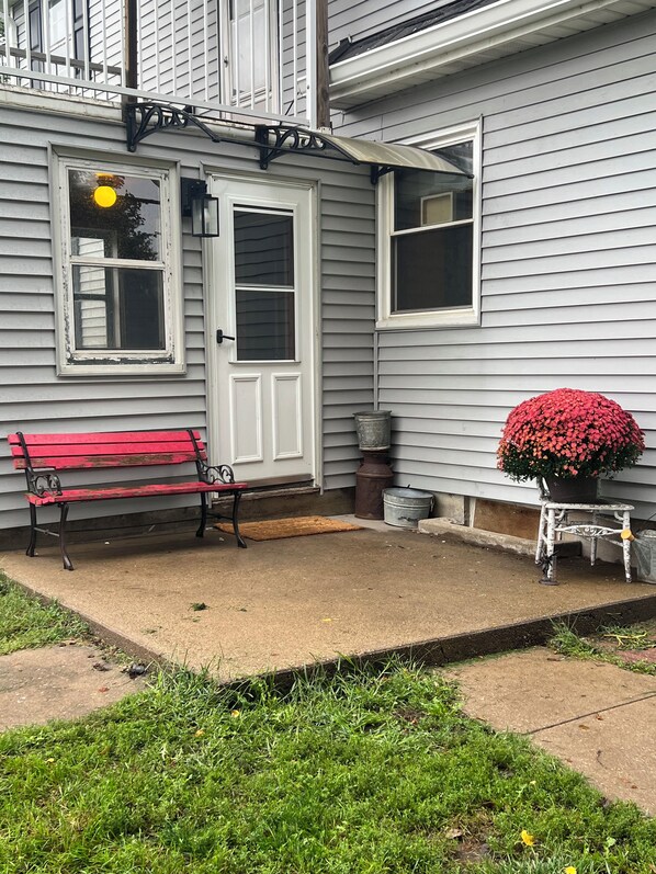 A house exterior with a red bench, a potted plant, and a door.