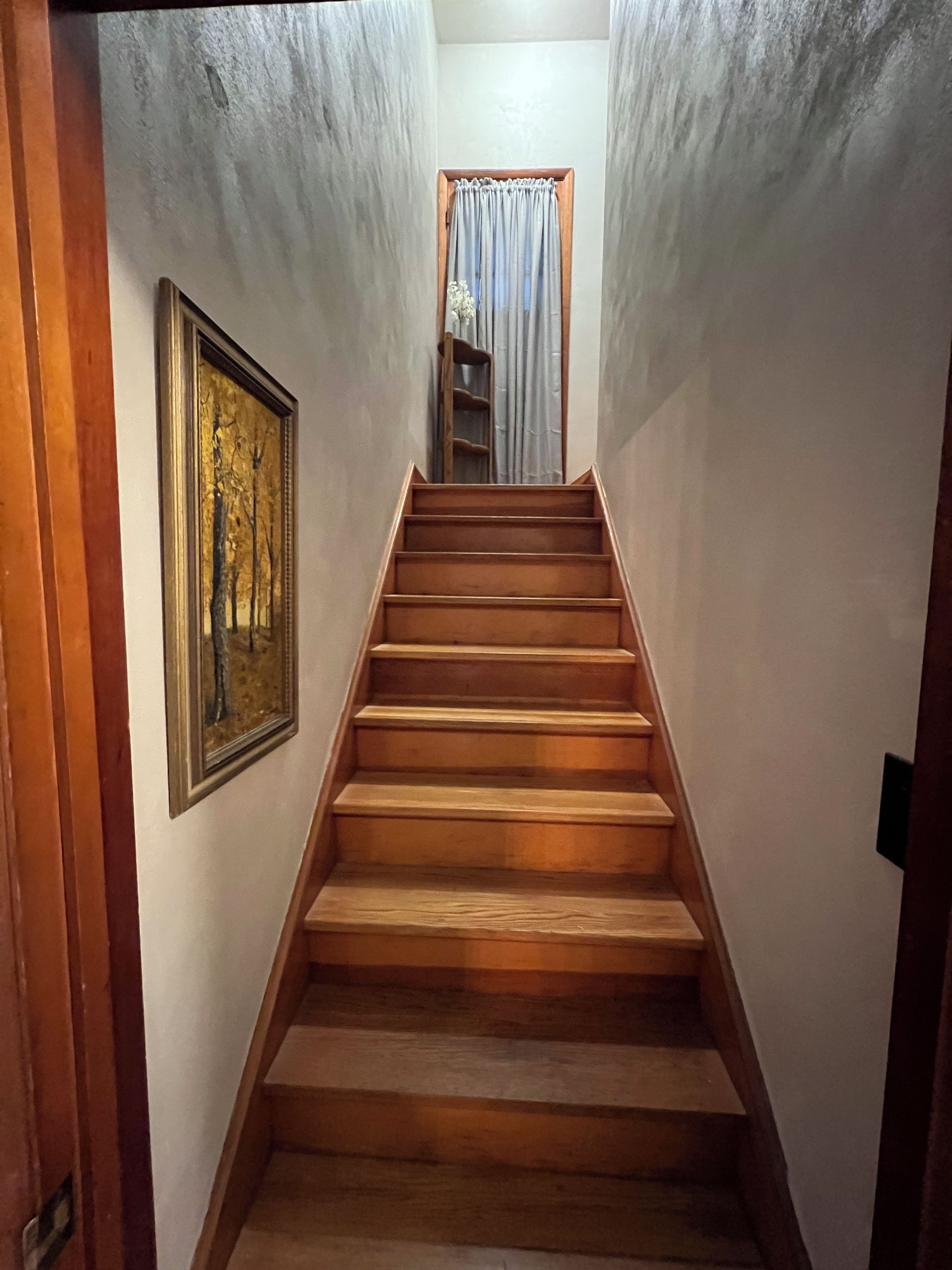 A wooden staircase leading to a landing with a framed picture on the wall.