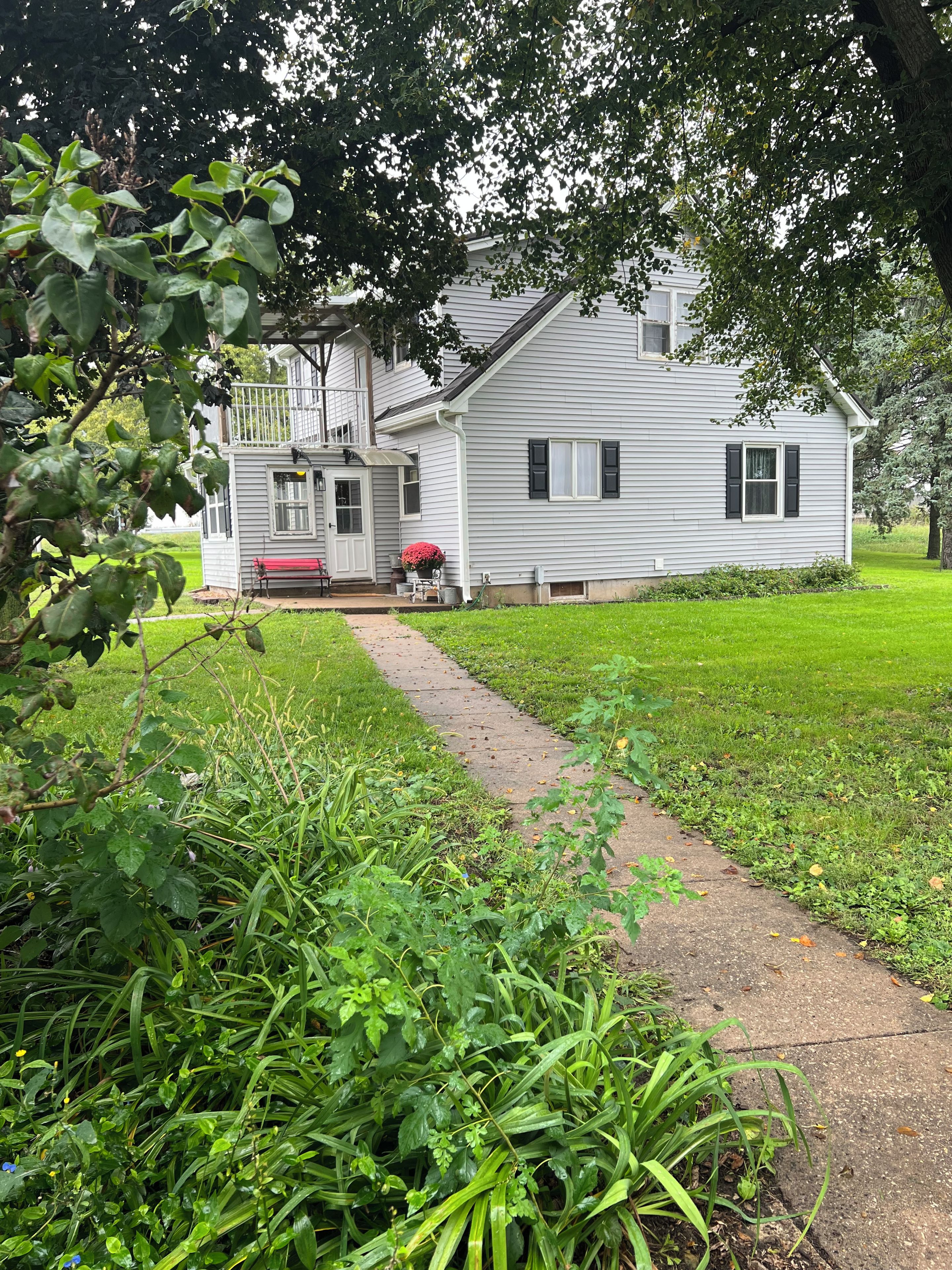 A white house with a covered porch and a red bench.