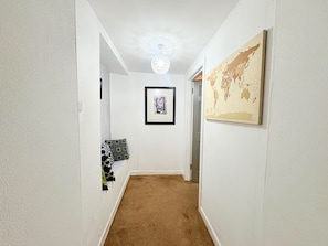 Un pasillo con piso alfombrado, un cuadro en la pared y una obra de arte con un globo terráqueo.