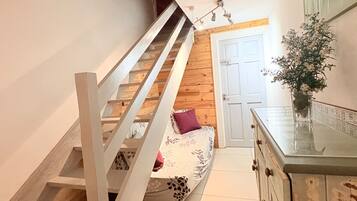 A staircase leading to a bedroom with a bed, a dresser, and a door.