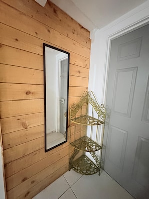 Un coin avec un mur en bois, une porte blanche et une étagère en métal.