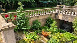 A garden with a stone balustrade, various plants, and a black container. - Victorian Apt, Sleeps 2-4 With Private Garden (Londonderry)