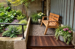 A wooden bench in a garden area with various plants and a stone wall.