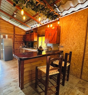 Uma cozinha rústica com armários de madeira, uma mesa de jantar de madeira e luminárias pendentes.