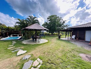 Ein Garten mit Swimmingpool, einer überdachten Sitzgelegenheit und einer Terrasse mit Gartenmöbeln.