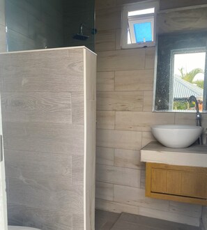 Ein Badezimmer mit einem Holzbadezimmer-Möbelstück, einem weißen Waschbecken und einem Spiegel darüber.