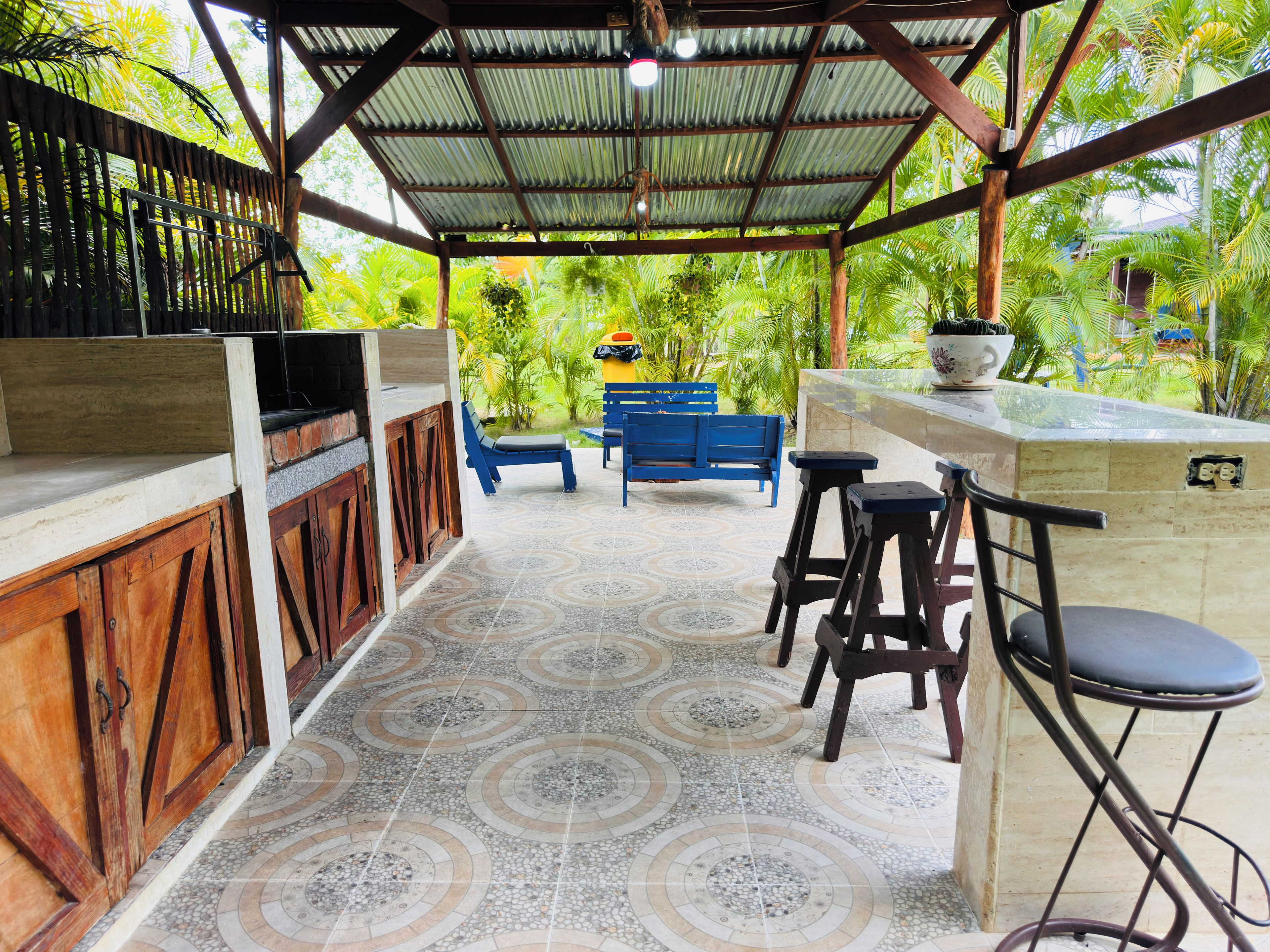 An outdoor patio with a grill, bar stools, and a blue bench.
