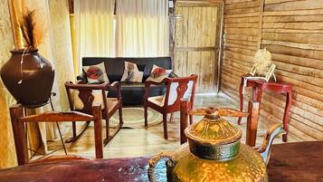 A rustic interior with a wooden table, a sofa, and chairs. A decorative teapot is on the table.