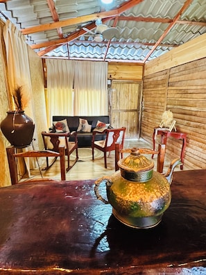 Um interior rústico com uma mesa de madeira, um sofá e cadeiras. Um bule decorativo está sobre a mesa.