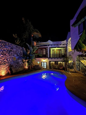 A nighttime view of a resort with a swimming pool, a stone wall, and a two-story building with illuminated windows. - Santoria Restaurante & Hotel (San Miguel de Allende)