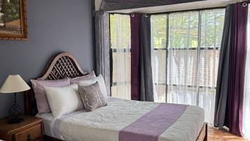 Quarto com duas camas, cabeceira de madeira, mesa de cabeceira e janela com cortinas.